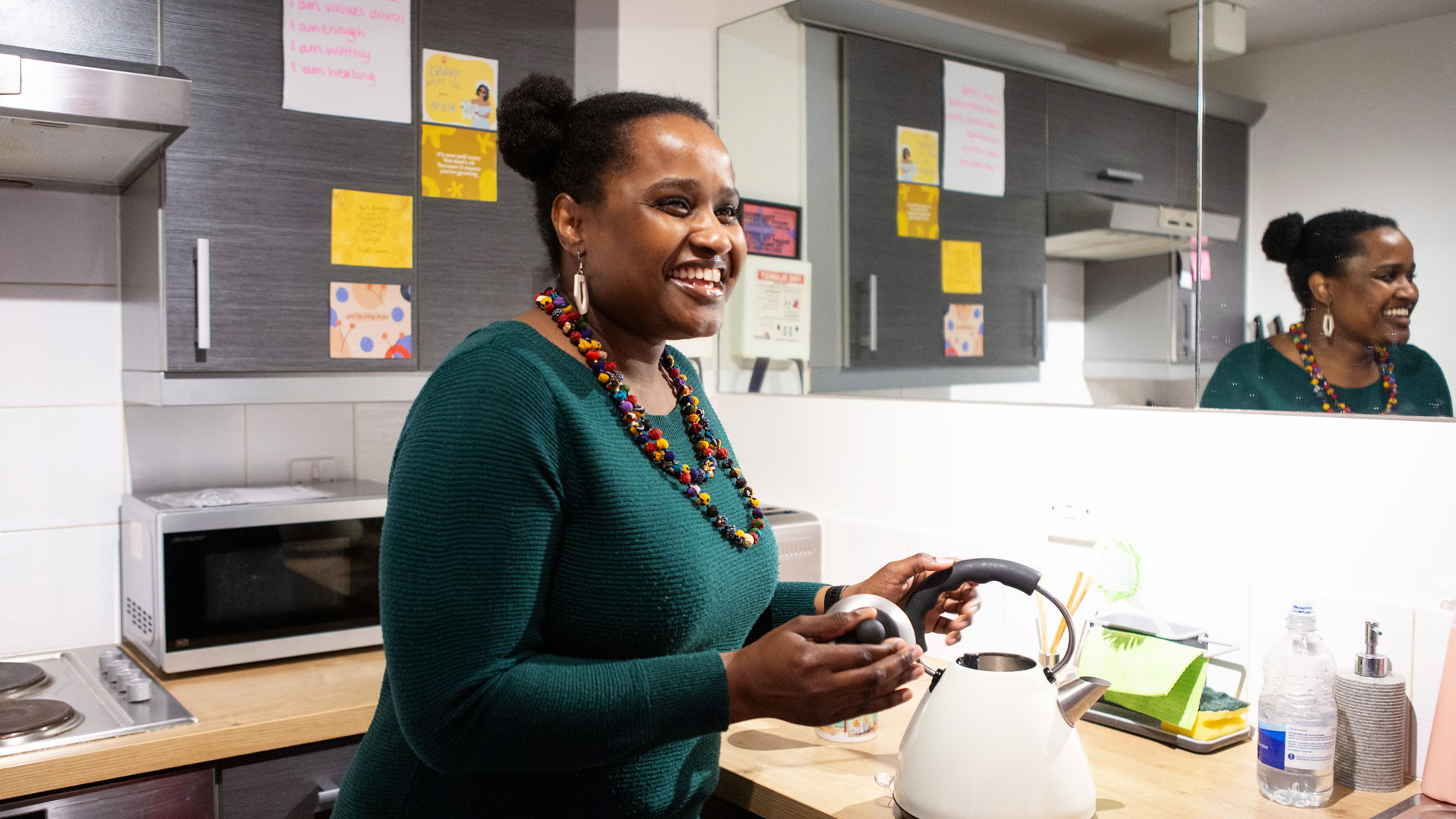 Woman making a tea in the kitchen laughing